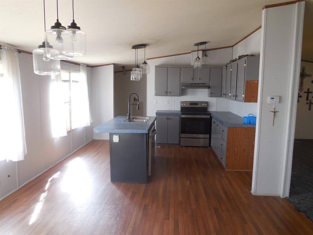 800 Melvin Street Ranger, TX 76470 - Photo 19 of 19 Kitchen with sink, electric stove, an island with sink, dark hardwood / wood-style flooring, and hanging light fixtures