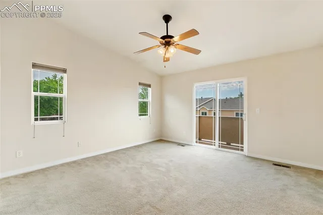 an empty room with windows and ceiling fan