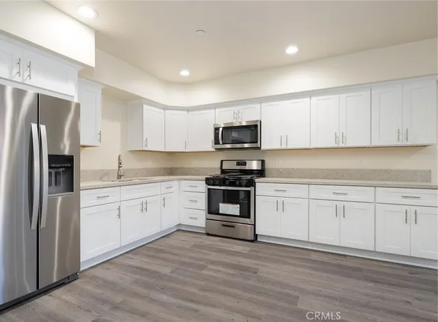 a kitchen with granite countertop white cabinets and stainless steel appliances