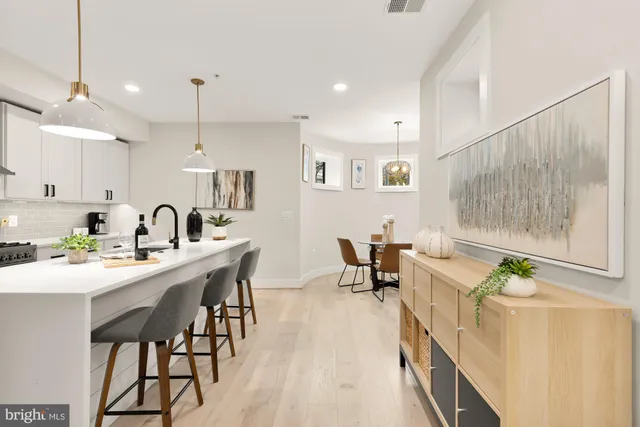 a kitchen with stainless steel appliances kitchen island granite countertop a dining table chairs and white cabinets