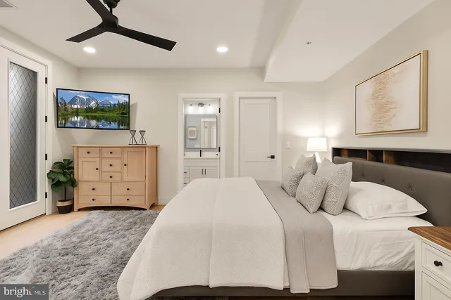 a bedroom with a large bed and a flat tv screen on dresser