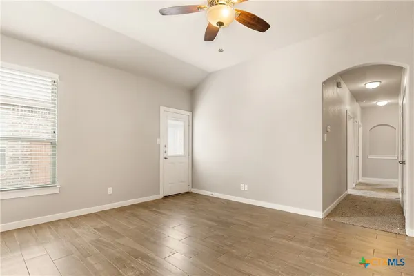 an empty room with wooden floor cabinet and windows