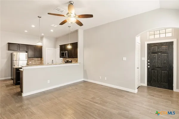 a view of kitchen with stainless steel appliances kitchen island a sink a refrigerator and a view of living room