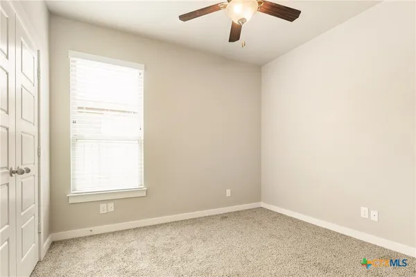 an empty room with a window and a ceiling fan