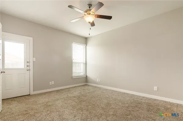 an empty room with a window and a fan