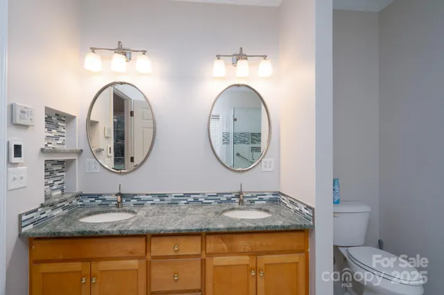a bathroom with a granite countertop double vanity sink and a mirror