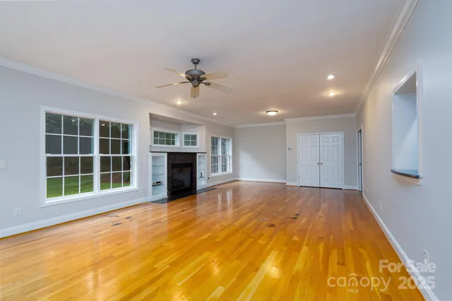 a view of an empty room with a window and a kitchen