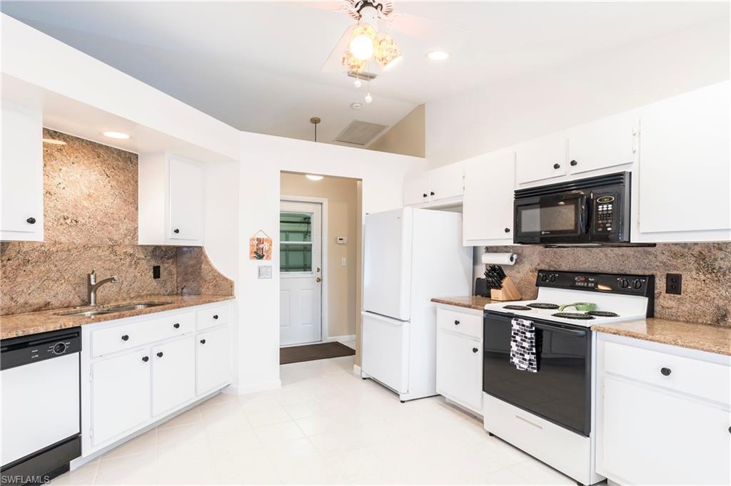 124 Versailles Circle Naples, FL 34112 - Photo 7 of 19 a kitchen with granite countertop a sink stove and refrigerator