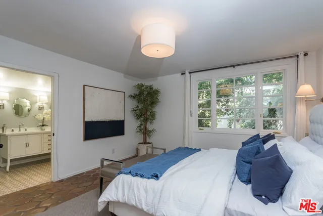 a bedroom with a large bed and a flat tv screen on dresser