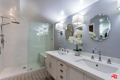 a bathroom with a double vanity sink mirror and shower