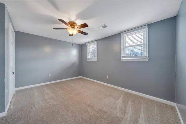 an empty room with windows and fan