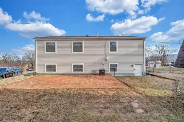 a view of house with backyard and trees in the background