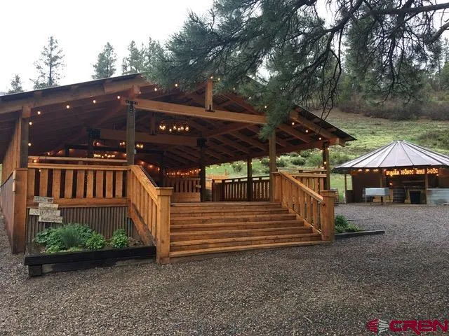 a view of a patio with table and chairs a barbeque with wooden floor and roof