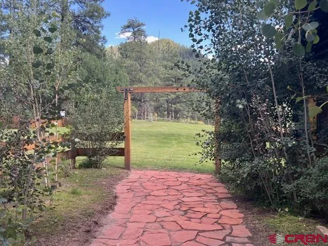 a view of a patio with table and chairs potted plants and a large tree