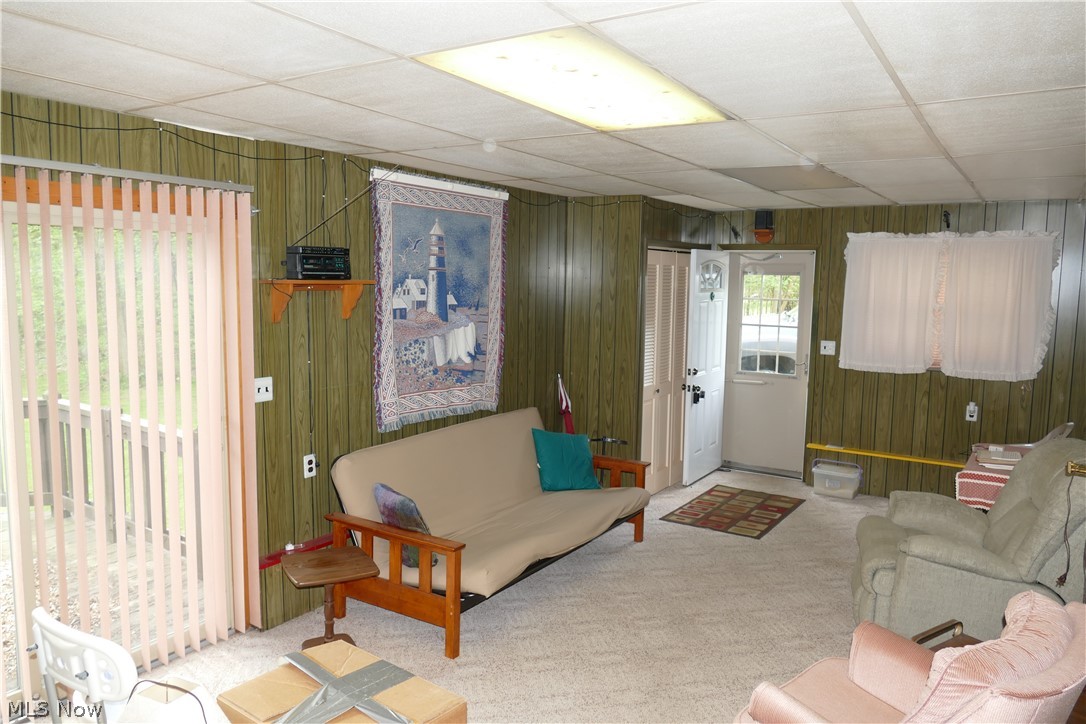 8661 Ravenna Road Chardon, OH 44024 - Photo 14 of 16 Carpeted living room featuring a paneled ceiling and wooden walls