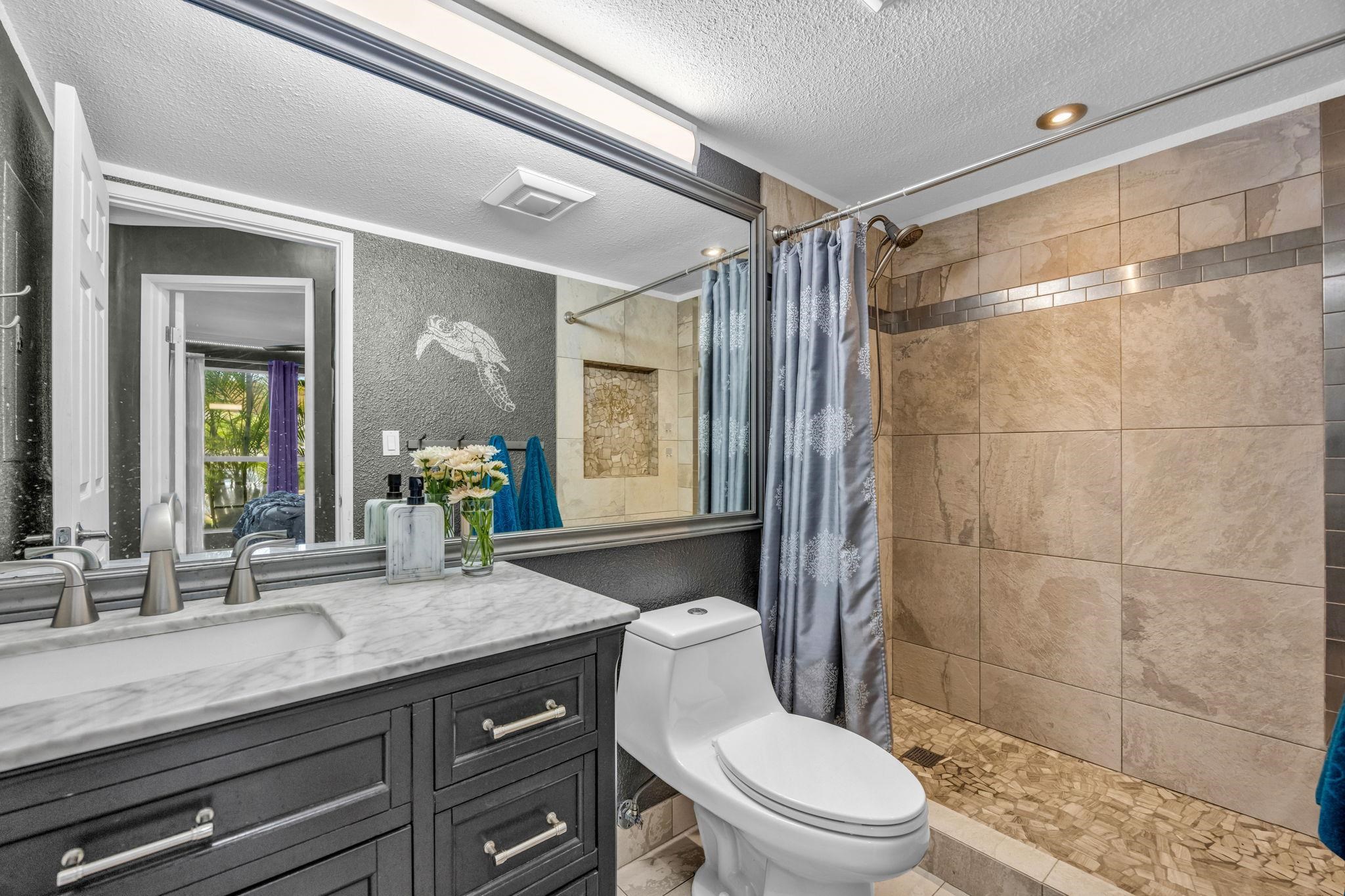 160 Keonekai Road, Unit 13102 Kihei, HI 96753 - Photo 18 of 36 a bathroom with a granite countertop sink a toilet a mirror and shower