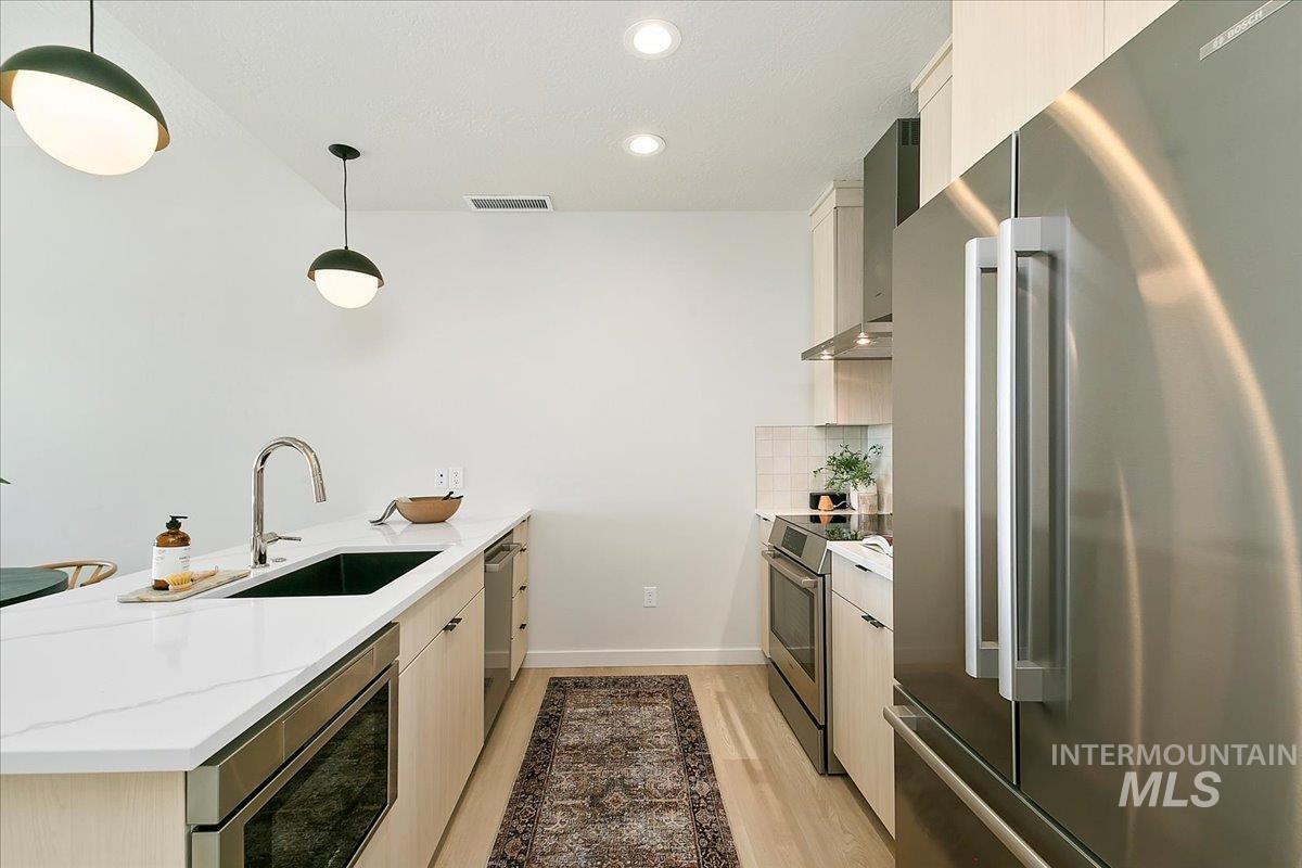 4430 East Haystack Street, Unit 109 Boise, ID 83716 - Photo 9 of 43 Kitchen featuring appliances with stainless steel finishes, a peninsula, hanging light fixtures, recessed lighting, and light stone counters