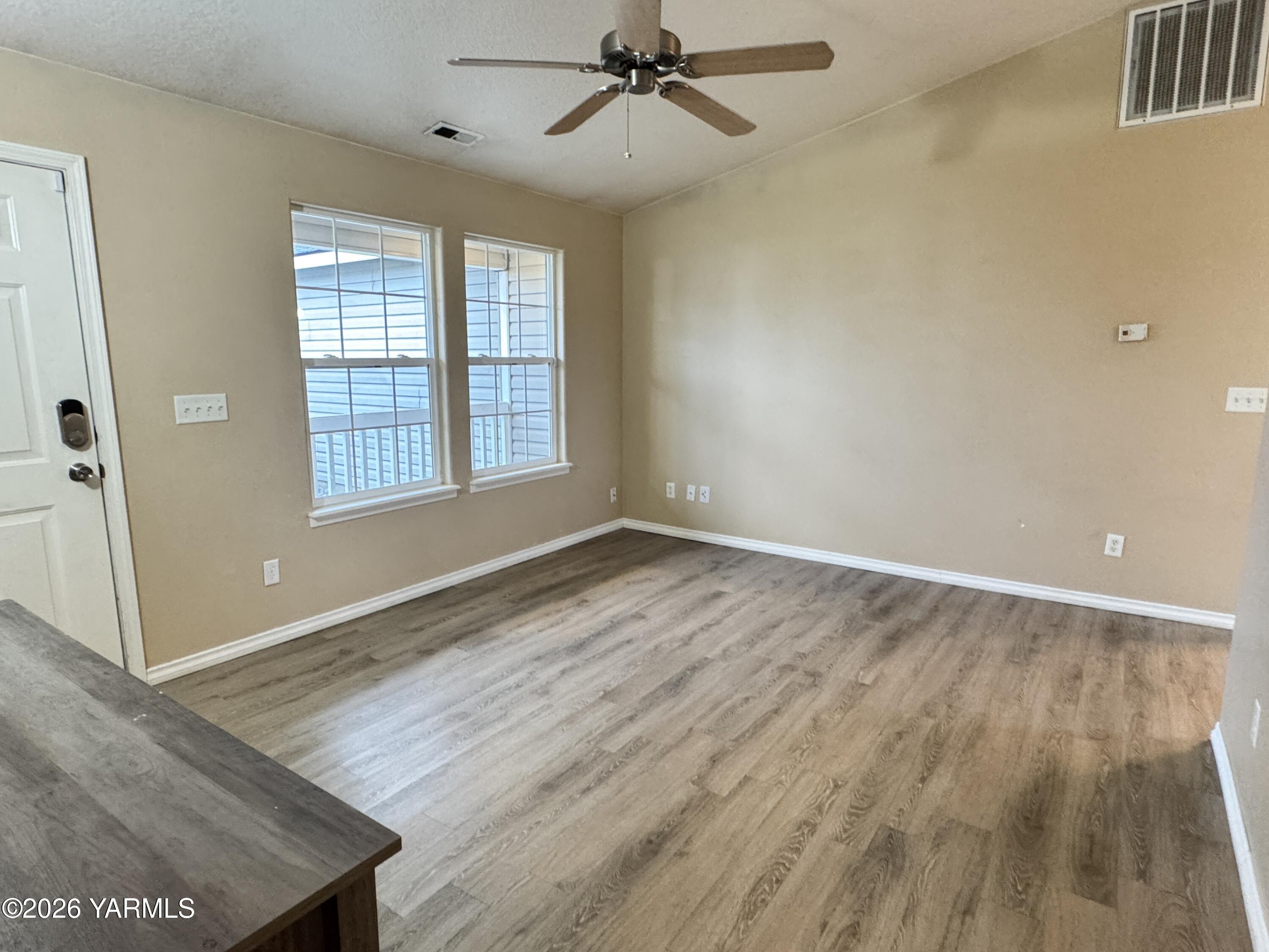 815 Jessica Court Grandview, WA 98930 - Photo 5 of 27 an empty room with wooden floor fan and windows