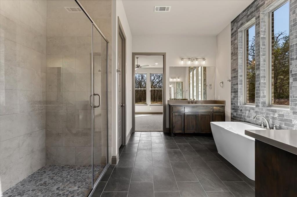 131 Spring Valley Road Paradise, TX 76073 - Photo 22 of 40 a bathroom with a double vanity sink a mirror a shower and a bathtub