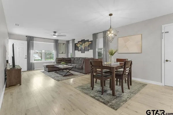 a dining room with wooden floor a chandelier a wooden table and chairs