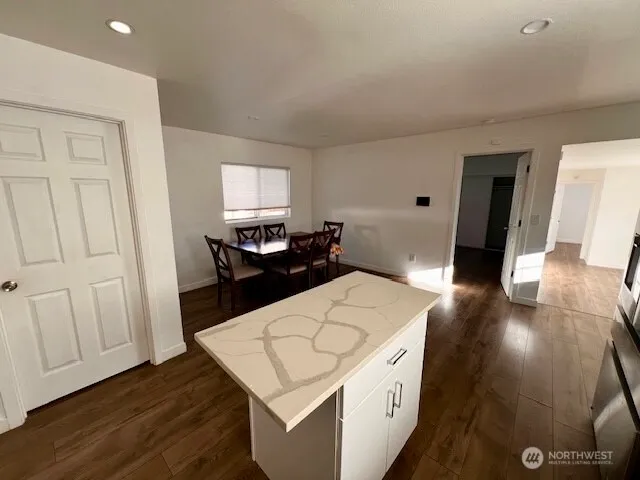 a living room with a couch and a dining table with wooden floor