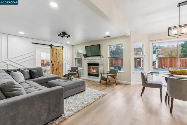 a living room with furniture fireplace and large windows