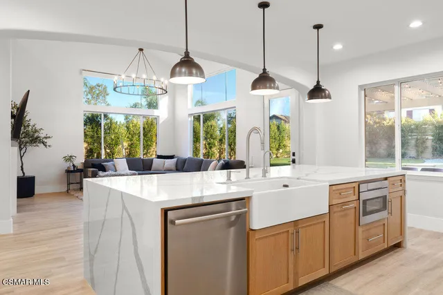 a kitchen with stainless steel appliances granite countertop a sink a island a stove and a wooden floor