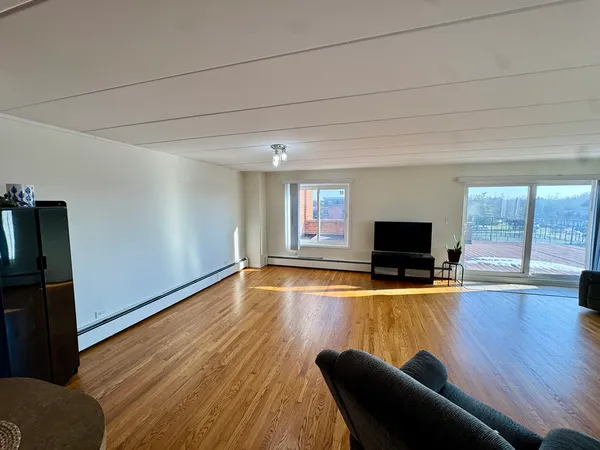 a large living room with stainless steel appliances granite countertop a stove and a wooden floors