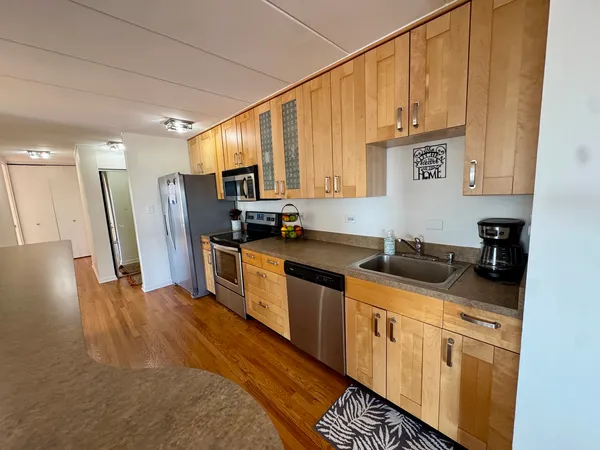 a kitchen with stainless steel appliances granite countertop a refrigerator a stove and a wooden floor