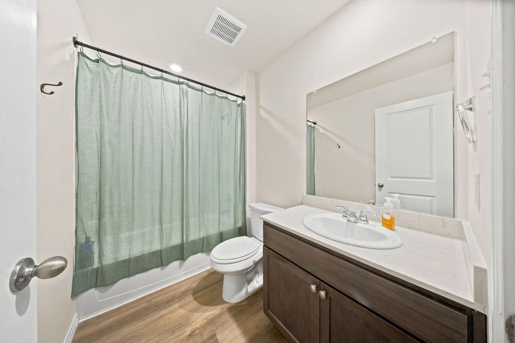 822 Ramble Road Lavon, TX 75166 - Photo 17 of 35 Bathroom featuring a dark wood-finish vanity with a light countertop, an undermount sink with chrome fixtures, a wall-mounted mirror, and wood-finish flooring