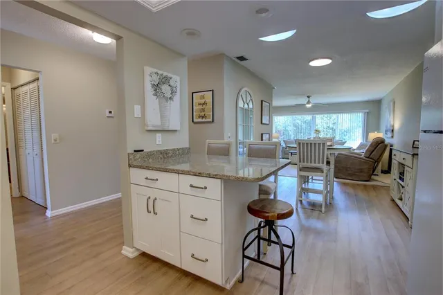 a kitchen with granite countertop a dining table chairs refrigerator and cabinets