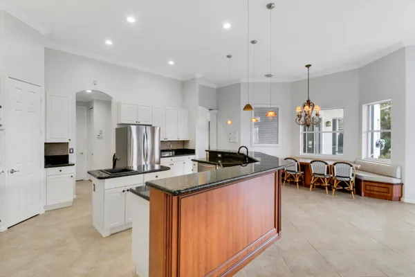 a kitchen with kitchen island granite countertop a sink and white cabinets