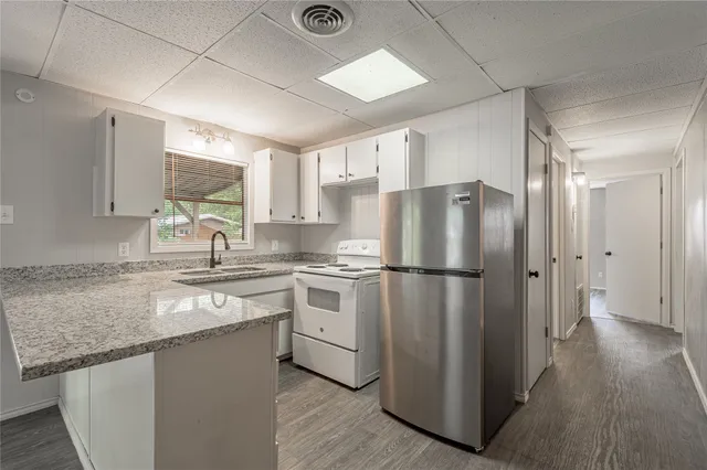 a kitchen with a sink a refrigerator a window and cabinets