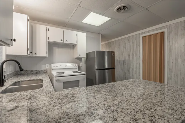 a kitchen with stainless steel appliances granite countertop a refrigerator sink stove and white cabinets