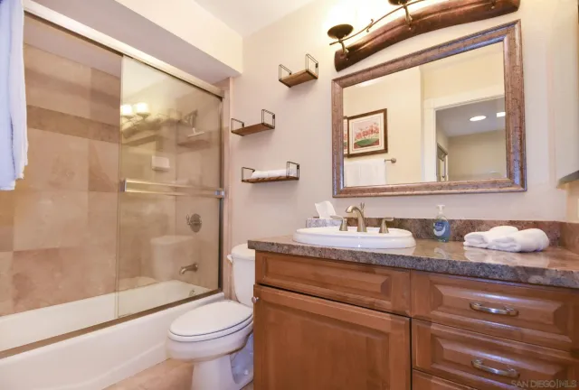 a bathroom with a granite countertop sink mirror vanity and toilet