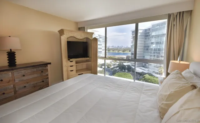 a bedroom with a bed and large window with balcony view