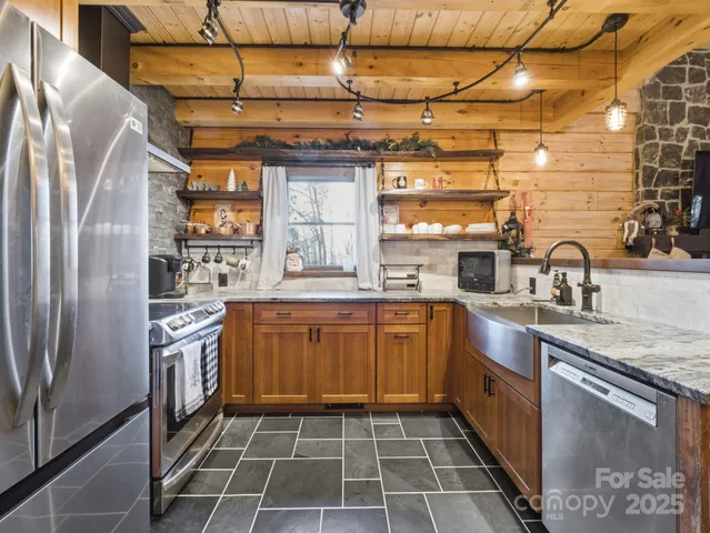 a kitchen with stainless steel appliances granite countertop a sink a stove a refrigerator and cabinets