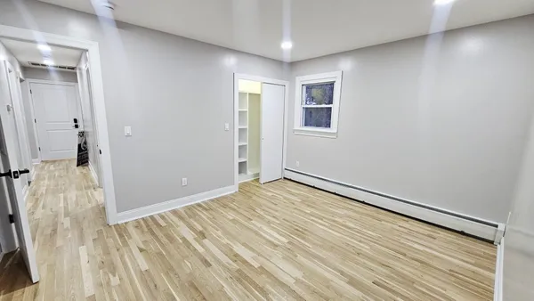 a view of empty room with wooden floor and fan