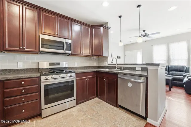 a kitchen with stainless steel appliances granite countertop a stove a sink and a microwave