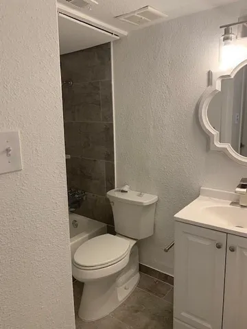 a white toilet sitting next to a bathroom sink and vanity