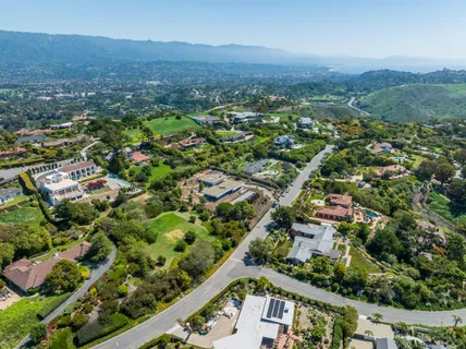 an aerial view of residential houses with outdoor space and trees