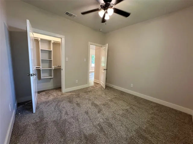 an empty room with wooden floor ceiling fan and windows