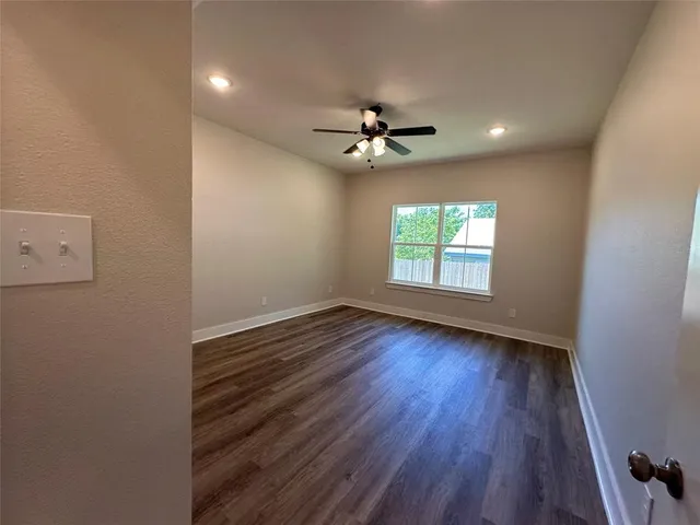 an empty room with wooden floor chandelier fan and windows