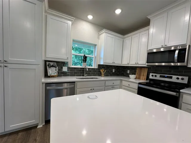 a kitchen with stainless steel appliances a stove a sink a center island and cabinets