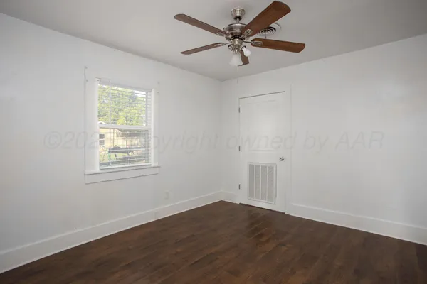 an empty room with wooden floor fan and windows