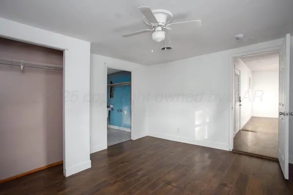 an empty room with wooden floor and ceiling fan