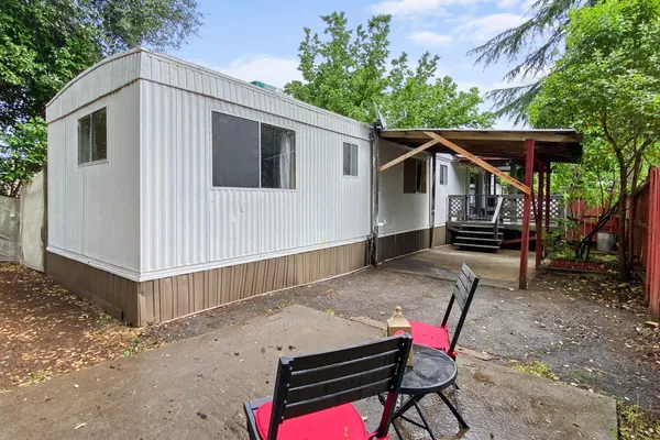 a view of a small house with wooden deck front of house