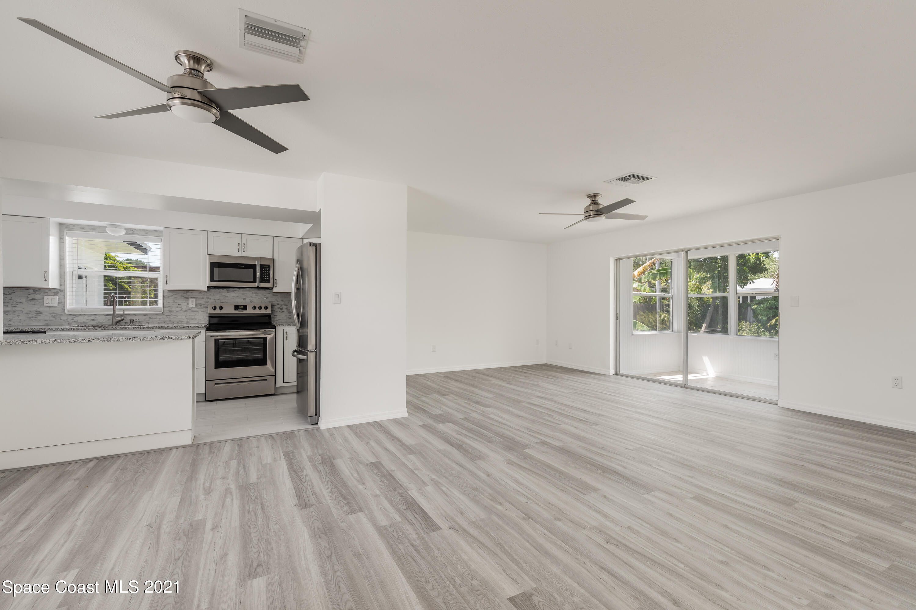 640 Java Road Cocoa Beach, FL 32931 - Photo 5 of 18 a view of a kitchen with wooden floor and a ceiling fan