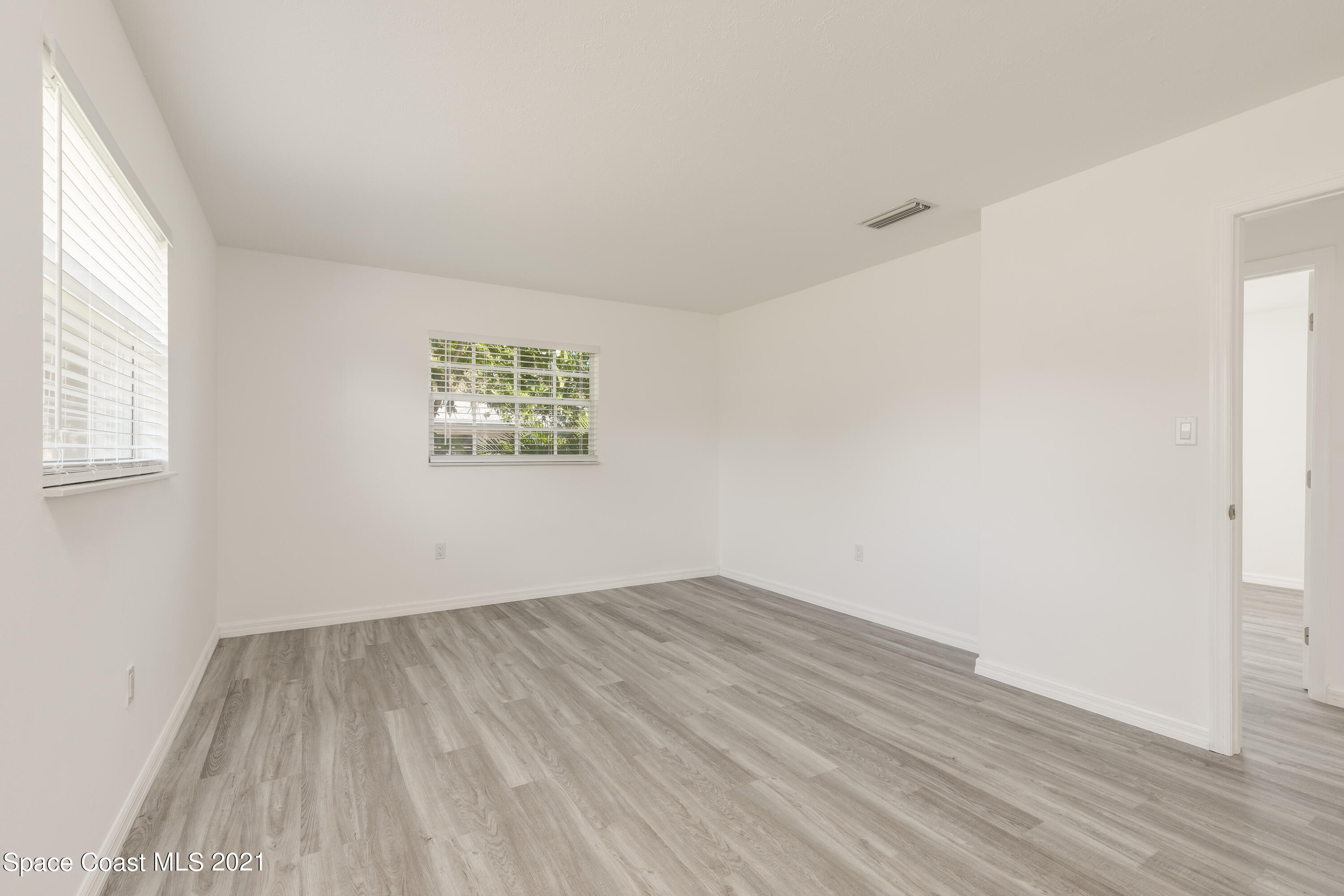 640 Java Road Cocoa Beach, FL 32931 - Photo 7 of 18 an empty room with wooden floor and windows