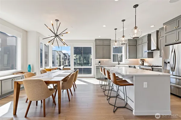a large kitchen with kitchen island a stove a sink dishwasher and a dining table with wooden floor